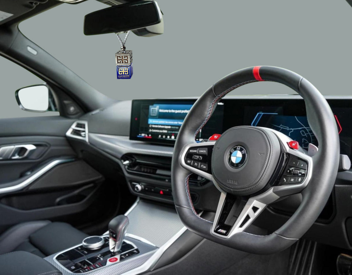 Car interior with a steering wheel and dashboard, featuring a car air freshener.